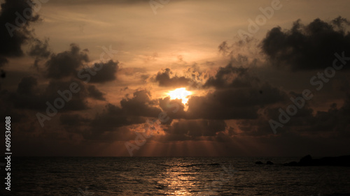 Dawn's Embrace: Sun Rising Behind Clouds Over the Sea
