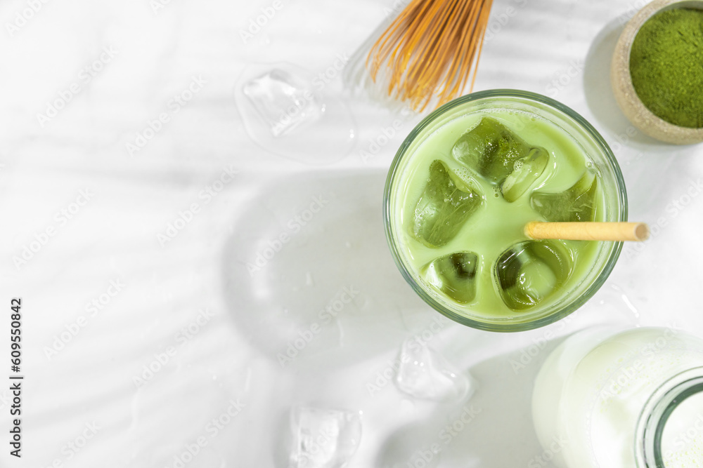 Iced green matcha latte in a glass on white background with hard shadows. Cold summer drink. Top view Iced green matcha latte in a glass on white background with hard shadows. Cold summer drink. Top view