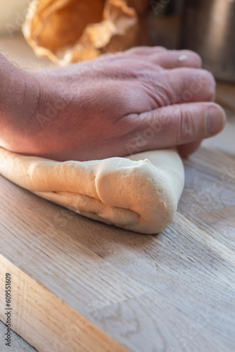 Man kneading dough on a wooden chopping board. Dough is yeast free flat bread mix