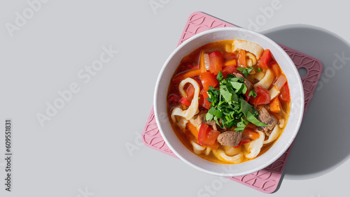 Lagman cooked soup with beef and vegetables on grey background. Copy space	
 photo