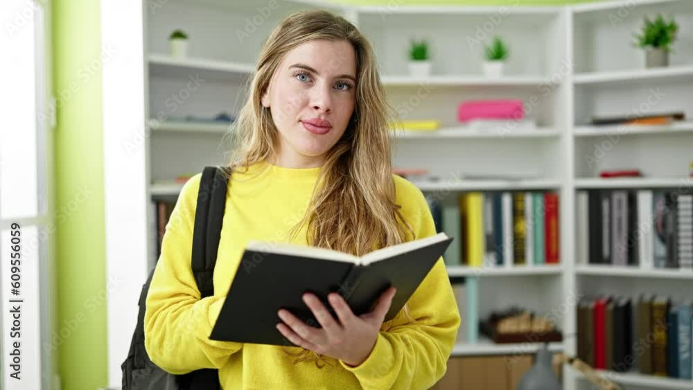 Young blonde woman student reading book doing silence gesture at library university Young blonde woman student reading book doing silence gesture at library university