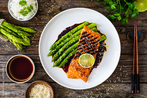 Grilled salmon steak with green asparagus in teriyaki sauce on wooden table 