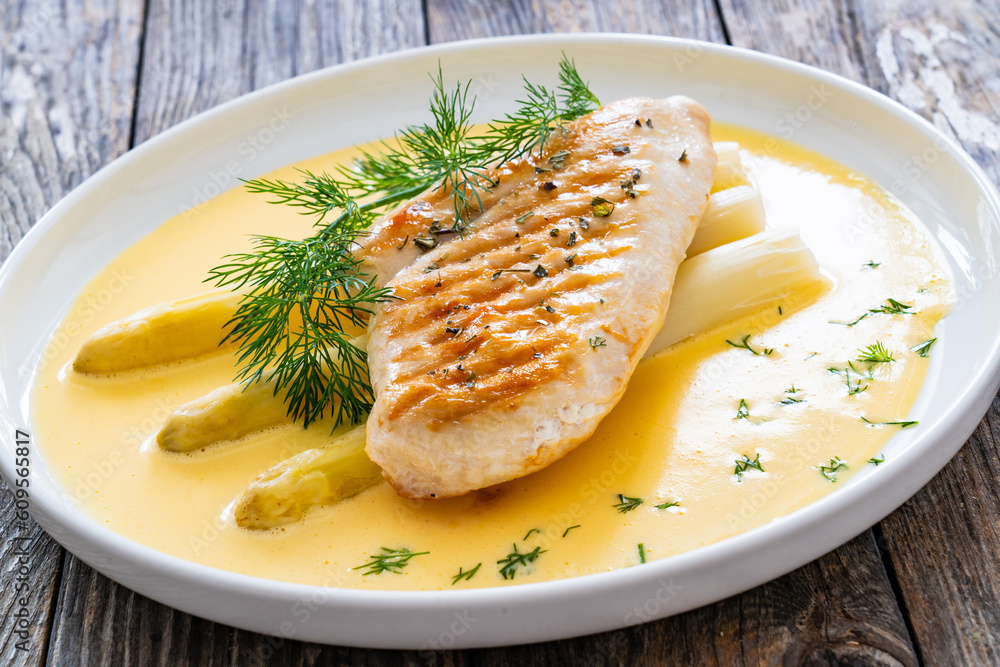 Grilled chicken breast and white asparagus in hollandaise sauce on wooden table
Grilled chicken breast and white asparagus in hollandaise sauce on wooden table