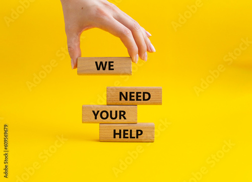 We need your help symbol. Wooden blocks with words We need your help. Beautiful yellow background. Businessman hand. Business and We need your help concept. Copy space.