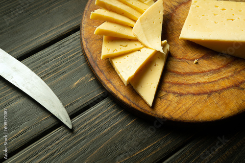 Sliced pieces of cheese with a knife on a cutting board. Fast food or street food concept on vintage table. Cheese tasting