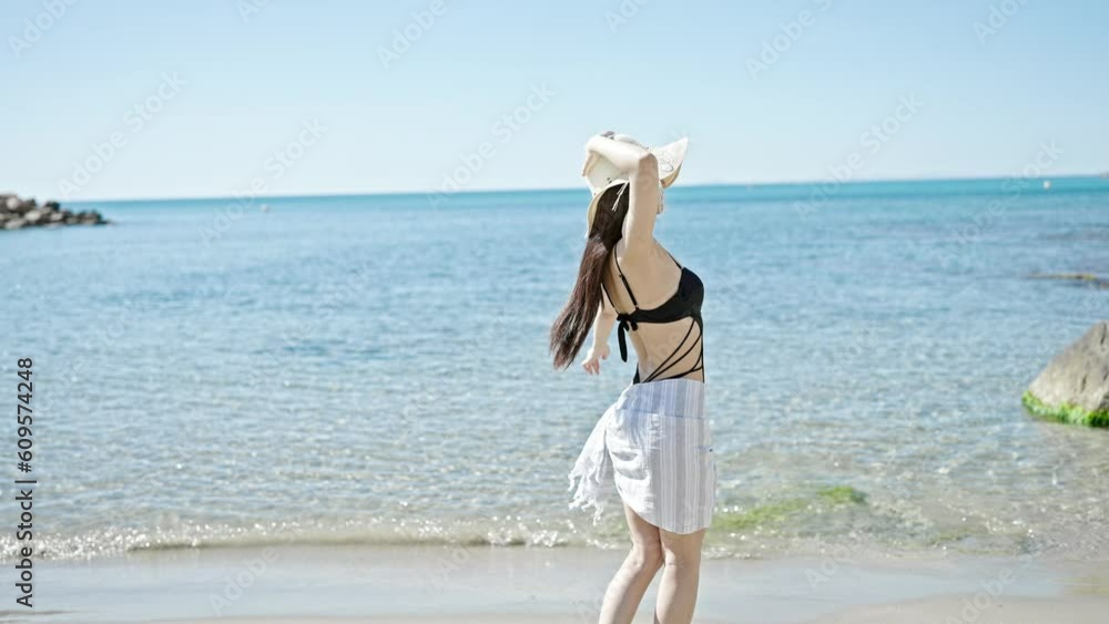 Young chinese woman tourist wearing swimsuit dancing at seaside Young chinese woman tourist wearing swimsuit dancing at seaside