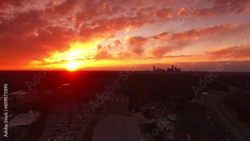 Aerial Shot Of Cars On Freeway By Bojangles Coliseum At Sunset, Drone Flying Backward Over City Against Cloudy Orange Sky - Charlotte, North Carolina photo