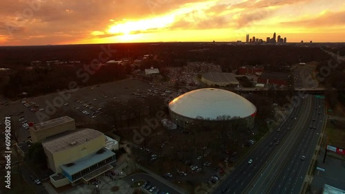 Aerial Shot Of Bojangles Coliseum By Freeway At Sunset, Drone Ascending Backward Over City Against Cloudy Orange Sky - Charlotte, North Carolina photo