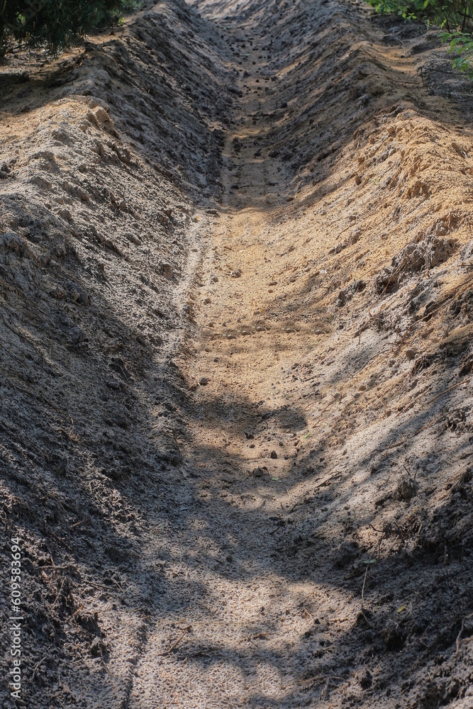 long trench fire ditch made of gray brown sand outdoors in the forest long trench fire ditch made of gray brown sand outdoors in the forest
