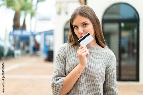 Wallpaper Mural Young pretty blonde woman holding a credit card and thinking Torontodigital.ca