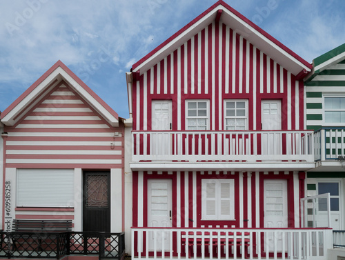 Contrast of houses of different colors and sizes. Facades of colorful striped houses in Costa Nova, Aveiro, Portugal. Details in red and pink.
