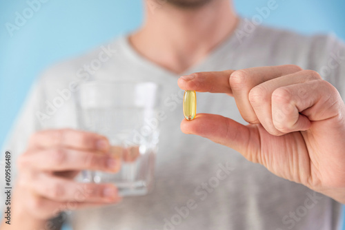 Dietary supplements. Man and holding omega 3 capsule with glass of water. Morning dose of vitamin. Fish oil in pills