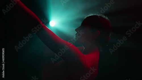 Female ballet dancer illuminated by blue and red lights move smoothly to music. Young attractive woman dancing in spotlight rays. Choreography, art, femininity