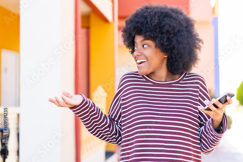 African American girl using mobile phone at outdoors with surprise facial expression