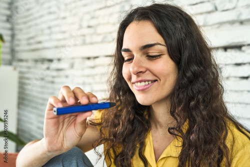 A young Caucasian woman, seated on the sofa, enjoying a vaping device as a healthier alternative to smoking.