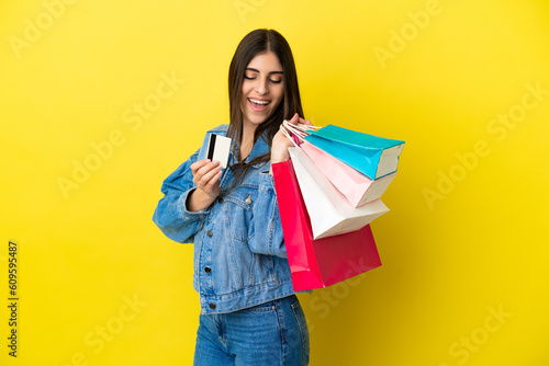 Young caucasian woman isolated on blue background holding shopping bags and a credit card