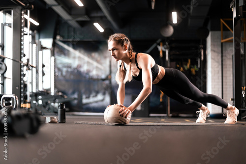 Fototapeta Naklejka Na Ścianę i Meble -  Fit and muscular woman exercising with medicine ball at gym.