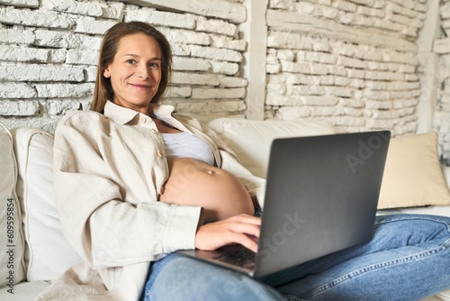 Pregnant woman, serene morning with laptop on sofa © Asier