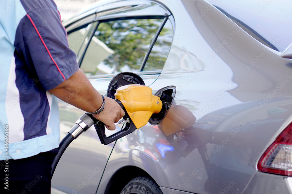 Naklejka premium A man uses his hand to open a gasoline or diesel nozzle. To fill a car parked at a gas station with a gasoline or diesel dispenser.