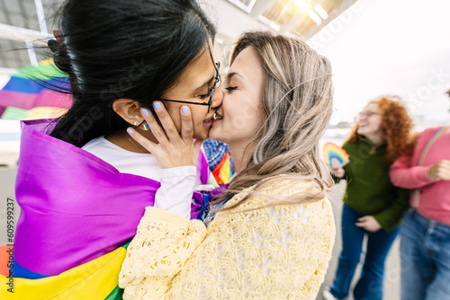 Photography Young female couple in love kissing during gay pride parade festival day
