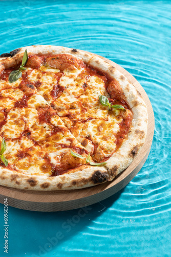 hot pizza on a wooden stand on a blue background water