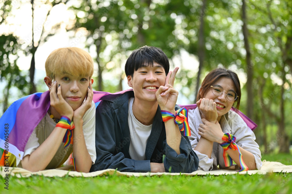 Pictured with a group of LGBT teenagers lying on the lawn, covered with rainbow flags and wearing a rainbow wristband, freedom concept, Celebration Pride month in June. Pictured with a group of LGBT teenagers lying on the lawn, covered with rainbow flags and wearing a rainbow wristband, freedom concept, Celebration Pride month in June.