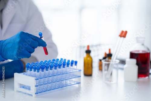 Принти на полотні Doctor hand taking a blood sample tube from a rack with machines of analysis in the lab background, Technician holding blood tube test in the research laboratory