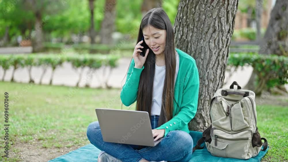 Young chinese woman talking on smartphone using laptop at park Young chinese woman talking on smartphone using laptop at park