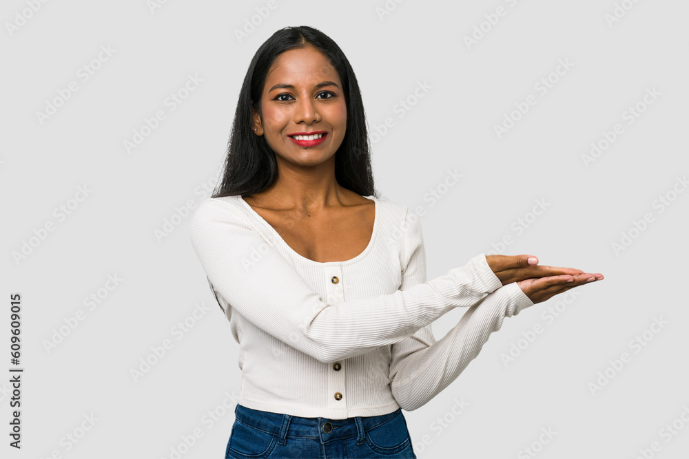 Young Indian woman cut out isolated on white background holding a copy space on a palm. Young Indian woman cut out isolated on white background holding a copy space on a palm.