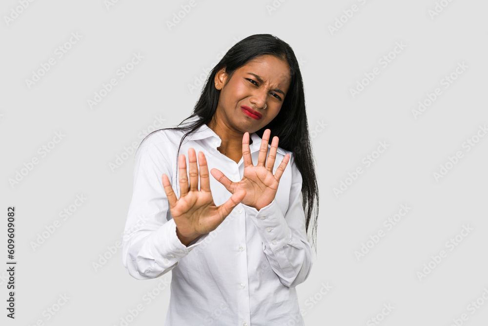 Young Indian woman cut out isolated on white background rejecting someone showing a gesture of disgust. Young Indian woman cut out isolated on white background rejecting someone showing a gesture of disgust.
