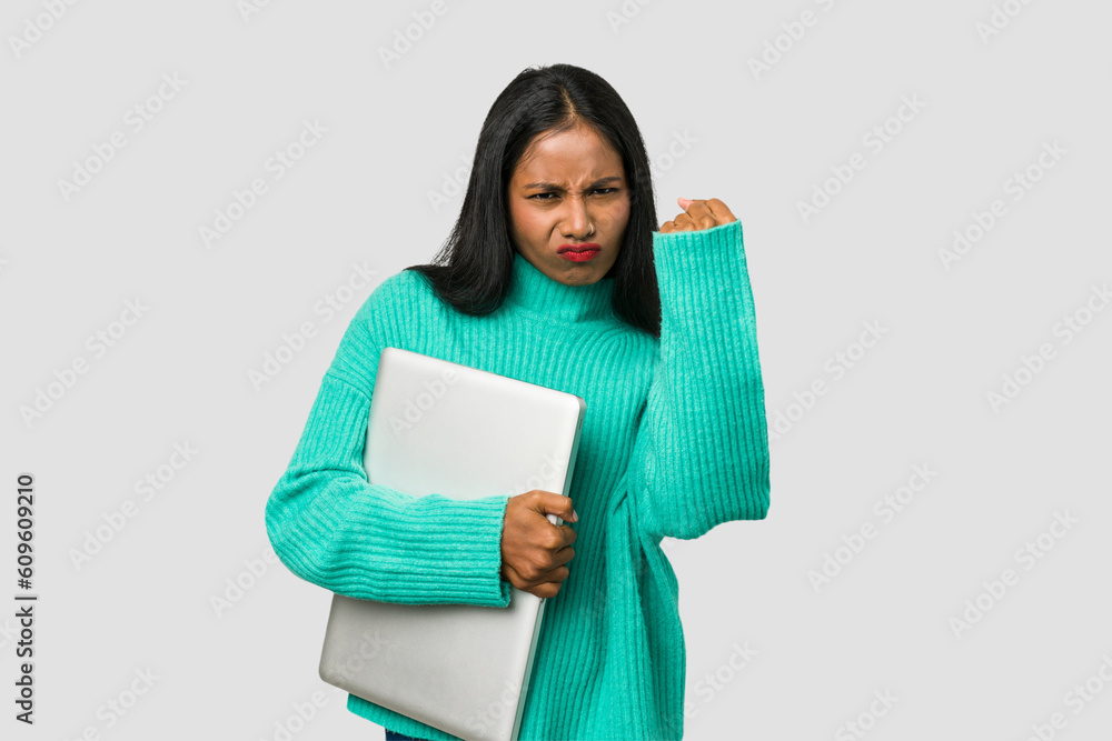 Fototapeta premium Young indian woman holding a laptop isolated on white background