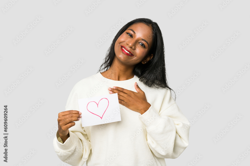 Young Indian woman holding a heart placard isolated on white background Young Indian woman holding a heart placard isolated on white background