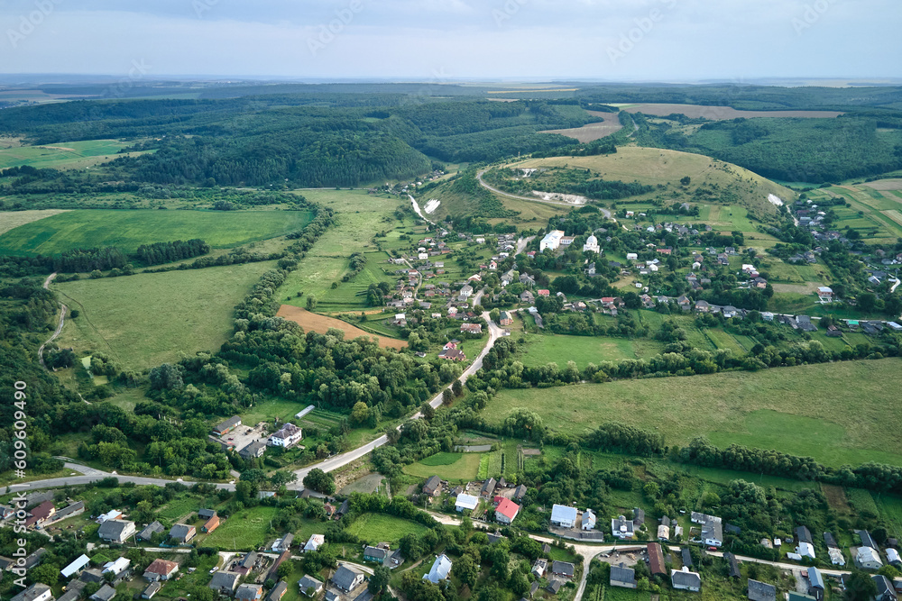 Aerial landscape view of green cultivated agricultural fields with growing crops and distant village houses