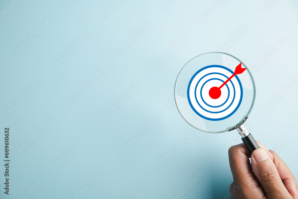 Φωτογραφία The magnifier glass centers on a target board, showcasing the importance of business objectives, it signifies the concepts of search, goal setting, strategy, and achieving success
