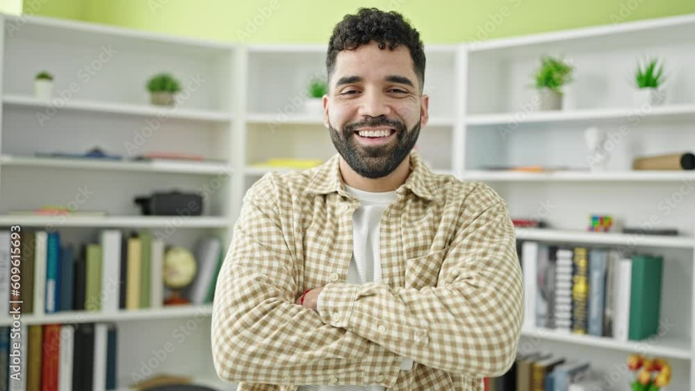 Young hispanic man student smiling confident standing with arms crossed gesture at library university Young hispanic man student smiling confident standing with arms crossed gesture at library university