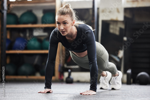 Fitness, push up and woman in gym for exercise, bodybuilder training and strong muscles. Healthy body, sports center and female person do pushup on floor for wellness, performance and cardio workout photo