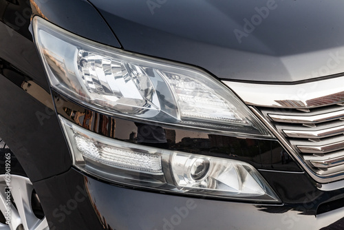 Front headlight view of car in black color after cleaning and detailing with washer before sale. Big lamp on vehicle with led drl. © Aleksandr Kondratov