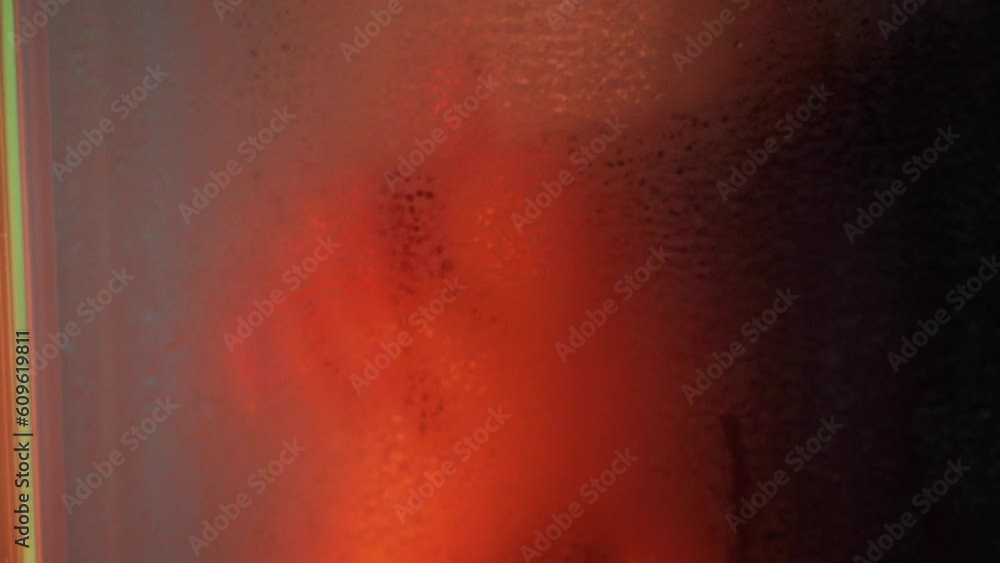 Beautiful sportive woman body in bath room, touch hand herself with passion under the water drops in slow motion. Neon background Beautiful sportive woman body in bath room, touch hand herself with passion under the water drops in slow motion. Neon background