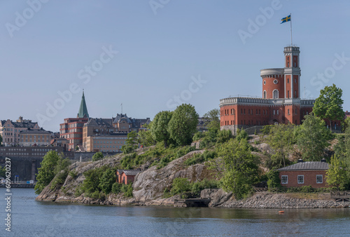 The castle on the island Kastellholmen, old church Sofia kyrkan and 1800s apartment houses in the background, a sunny summer day in Stockholm
