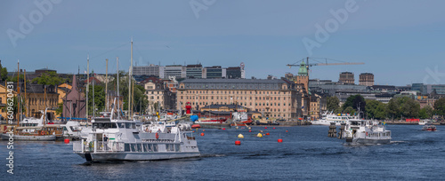 Ferries in the bay Ladugårdslandsviken, the pier Strandvägen with hotels apartments and boats, a sunny summer day in Stockholm