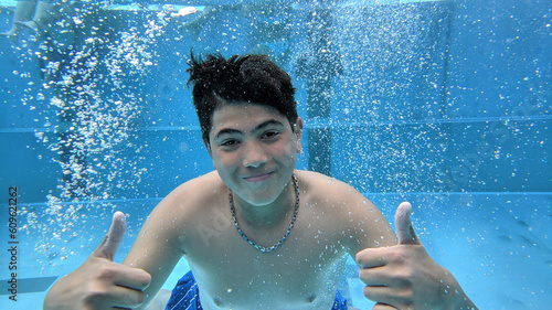 Teenager diving underwater showing thumbs up and smiling