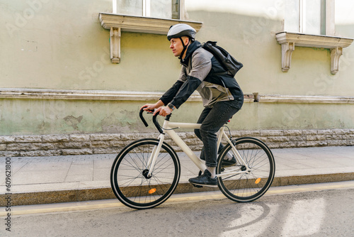 A male cyclist rides around the city in a helmet to the office with a bag. Urban transport for people.
