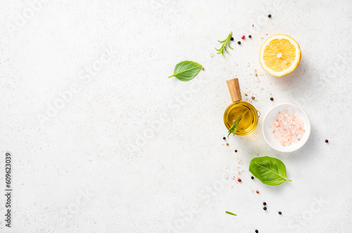 Various herbs and spices, oil in glass bowl and half of lemon on a white concrete background. Background for recipe, menu, text photo