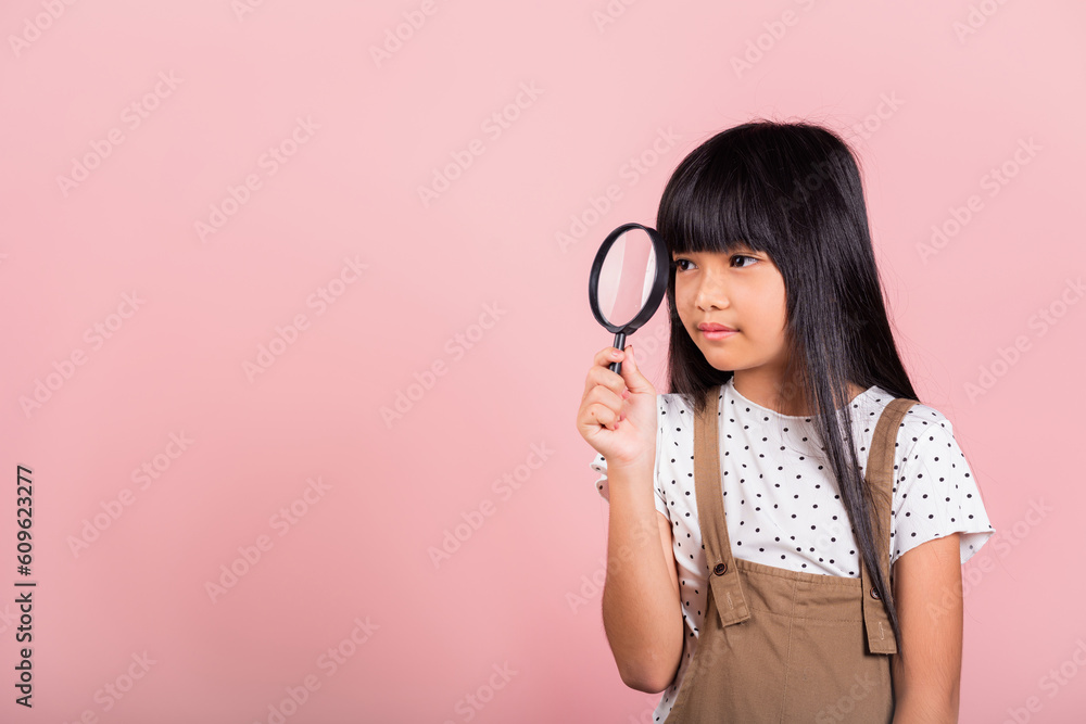 Asian little kid 10 years old funny looking through magnifying glass at studio shot isolated on pink background, Happy child girl lifestyle smiling exploring holding magnifier searching Asian little kid 10 years old funny looking through magnifying glass at studio shot isolated on pink background, Happy child girl lifestyle smiling exploring holding magnifier searching