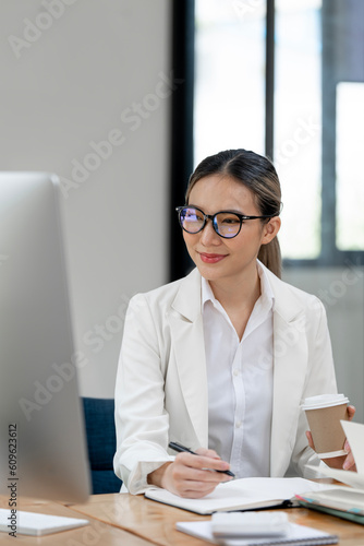 Portrait of young Asian businesswoman sitting taking notes in the office.