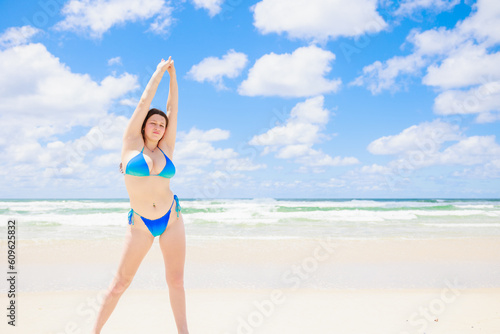 ビーチでストレッチをする水着姿の白人ティーンエイジャー photo