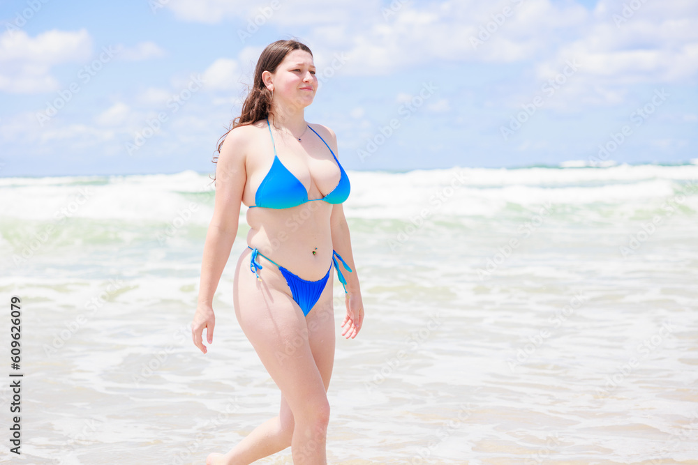 砂浜を歩く水着のセクシーなオーストラリア人女性
