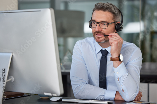 Businessman, call center and headphones on computer for customer service, telemarketing or support at office. Man, consultant or agent consulting on PC for online advice or telesales at the workplace photo