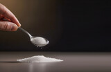White salt in a spoon on a black background in the hand. A slide of seasoning on the table. AI generated.