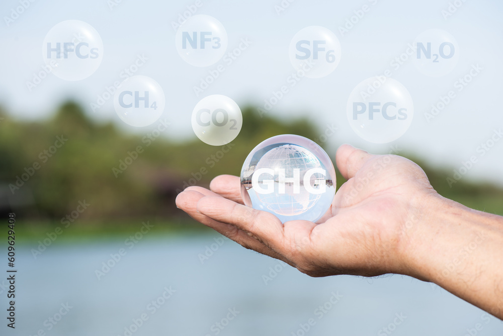 Crystal globe in male hand and text such as CH4 on nature background.Concept depicting the issue of carbon dioxide emissions and other gases its causing global warming. Crystal globe in male hand and text such as CH4 on nature background.Concept depicting the issue of carbon dioxide emissions and other gases its causing global warming.